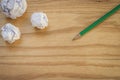 Top view of green pencil with many white crumpled paper ball put on wooden floor. Royalty Free Stock Photo
