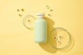 Top view of green plastic bottles of cream or lotion and with chamomilla flowers displayed on yellow background with petri dish. Royalty Free Stock Photo