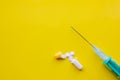 Green syringe with a needle and open yellow-white capsule with powder on a yellow background Royalty Free Stock Photo