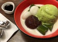 Top view of green tea matcha icecream scoop with red beans mochi and milk in red bowl