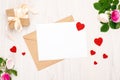 Top view greeting card with a red heart shapes and space for text, gift box with ribbon bow and rose flowers on a wooden Royalty Free Stock Photo