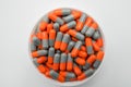 Top view of grey, orange, capsule pills in plastic container