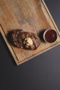 Top view of grilled bbq smoked meat steak with sauce on dark wooden board on black background, flat lay, copy space Royalty Free Stock Photo