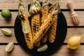 top view of grilled corn on plate surrounded by lime slices and lemon with squeezer on wooden Royalty Free Stock Photo