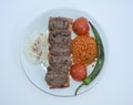 Top view of grilled meatballs, bulgur pilaf, roasted tomatoes and peppers served on white plate