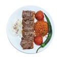 Top view of grilled meatballs, bulgur pilaf, roasted tomatoes and peppers served on white plate