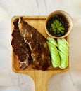 Top view of Grilled pork ribs, sliced cucumber and spicy sauce on wooden tray. Royalty Free Stock Photo