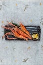 Top view of Grilled shrimps Giant Tiger Pawn with salt served with sliced lemon in black stone plate on washi Japanese paper