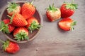 Top view group of fresh berry fruit, red strawberry in a brown wooden bowl and a half sliced on wooden floor with coppy space