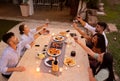 Top view of group of friends toasting with red wine glasses at sunset on a big white granite table in the garden laden with Royalty Free Stock Photo