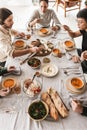 Top view of group of international friends sitting at the table full of different food dreamily eating together. Young Royalty Free Stock Photo
