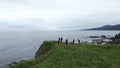Top view of group of tourists on edge of sea cliff. Clip. Hikers on edge of rocky coastline. Tourists on edge of cliff