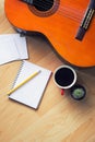 Top view guitar, coffee, cactus, notepad and pencil on wooden desk