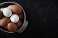 Top view of half a ceramic bowl of fresh organic brown and white eggs on dark background. Royalty Free Stock Photo