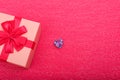 Top view of half of pink gift box on a Crimson backdrop and blue heart beside. Gift box in red ribbon with cold blue gems heart Royalty Free Stock Photo