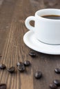 Top view of half white coffee cup with saucer and coffee beans, on dark wooden table, vertical, Royalty Free Stock Photo