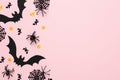 Top view Halloween decorations, bats, spiders, webs, confetti on pastel pink background with copy space. Happy Halloween holiday