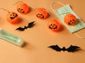 Halloween pumpkin lights , black paper bats,medical mask and alcohol sanitizer gel on orange background. Halloween , COVID-19 Royalty Free Stock Photo