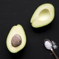 Top view, halved avocado and sea salt on black surface. Overhead, flat lay, from above Royalty Free Stock Photo