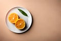 Top view of halved orange fruit on white plate on pastel color background