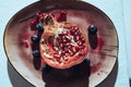 Top view of a halved pomegranate with blueberries on a plate