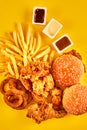 Top view hamburger, french fries and fried chicken on yellow background. Copy space for your text.