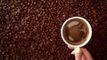 Top view of hand with cup of black coffe put it on coffe beans background Royalty Free Stock Photo