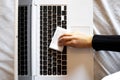 Top view of a hand disinfecting the laptop keyboard with a wipe