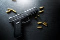 Top view of hand gun on black background with bullets around. 9mm pistol with ammunition on dark table.