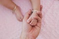 Top view of hand holding baby feet place on pink bed sheet Royalty Free Stock Photo