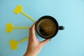 Top View of a Hand Holding a Black Cup of Coffee and Empty Yellow LAbels isolated on a BLue Background Royalty Free Stock Photo