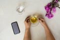 Top view hand holding cup of tea, flower, cell phone and glass o Royalty Free Stock Photo