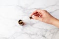 Top view of hand holding a retinol oil serum pipette and oil bottle on isolated marble background. Beauty care concept