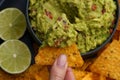 Top view of hand with tasty tortilla chips or nachos with fresh homemade guacamole dip sauce Royalty Free Stock Photo