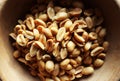 Top view of handful shelled peanuts in a wooden bowl