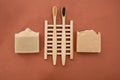 Top view of handmade bars of soap with bamboo toothbrushes on a small holder on a brown surface