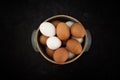 Top view of handmade ceramic bowl of fresh organic brown and white eggs on dark moody background. Royalty Free Stock Photo