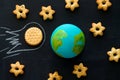 handmade model of Earth planet, cookie meteorite and cookies in the shape of stars on the chalkboard , space and