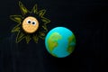 handmade model of Earth planet and cookie Sunwith funny googly eyes on the chalkboard , space and astronomy concept