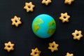 handmade model of Earth planet and cookies in the shape of stars on the chalkboard , space and astronomy concept