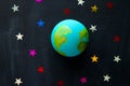 handmade model of Earth planet and sequins in the shape of stars on the chalkboard , space and astronomy concept