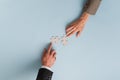 Top view of hands of businesswoman and businessman joining two matching puzzle pieces