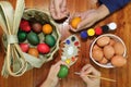 Top view of hands of family members are painting eggs with a paintbrush and palette on wooden table for preparing happy Easter day Royalty Free Stock Photo