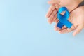 Top view of hands holding blue awareness ribbon. Prostate cancer, colon and colorectal cancer, peace, alopecia and arthritis care Royalty Free Stock Photo