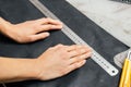 Top view of the hands of a leather craftsman. holds a metal ruler