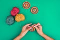 Top view of hands, making a round crochet pattern on green background with three balls of yarn and two ready motifs near Royalty Free Stock Photo