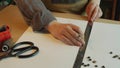 Top view the hands of a master shoemaker make a pencil drawing of the elements of a leather bag on paper. In the frame