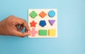 Top view Hands Picking up one Colorful Wooden building blocks in different shapes on blue background. Royalty Free Stock Photo