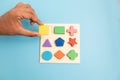 Top view Hands Picking up one Colorful Wooden building blocks in different shapes on blue background. Royalty Free Stock Photo