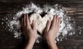 Top view of hands pressing, doing an indirect heart massage to a piece of dough in the shape of a heart, table with